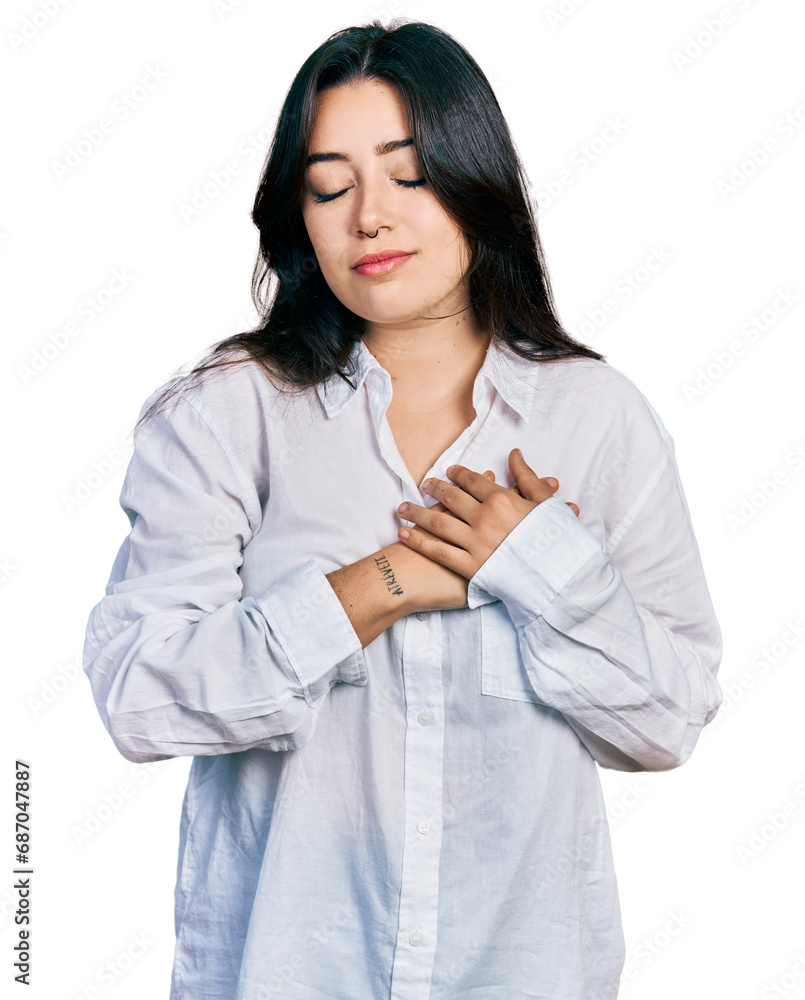 Beautiful hispanic woman wearing casual white shirt smiling with hands on chest with closed eyes and grateful gesture on face. health concept. Beautiful hispanic woman wearing casual white shirt smiling with hands on chest with closed eyes and grateful gesture on face. health concept.
