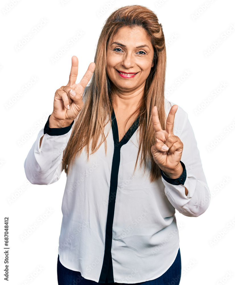 Middle age latin woman wearing business shirt smiling looking to the camera showing fingers doing victory sign. number two. Middle age latin woman wearing business shirt smiling looking to the camera showing fingers doing victory sign. number two.
