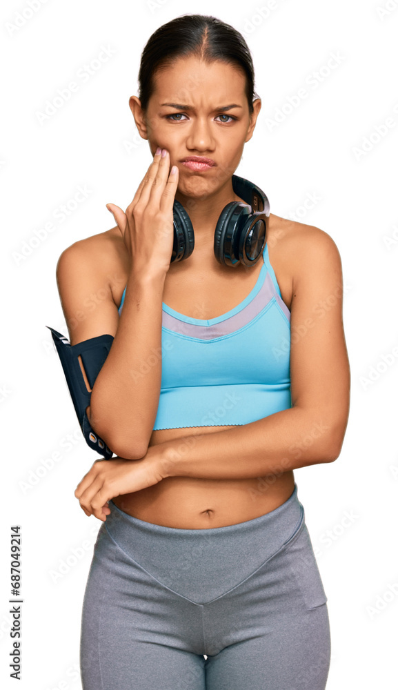 Beautiful hispanic woman wearing sportswear and headphones thinking looking tired and bored with depression problems with crossed arms. Beautiful hispanic woman wearing sportswear and headphones thinking looking tired and bored with depression problems with crossed arms.