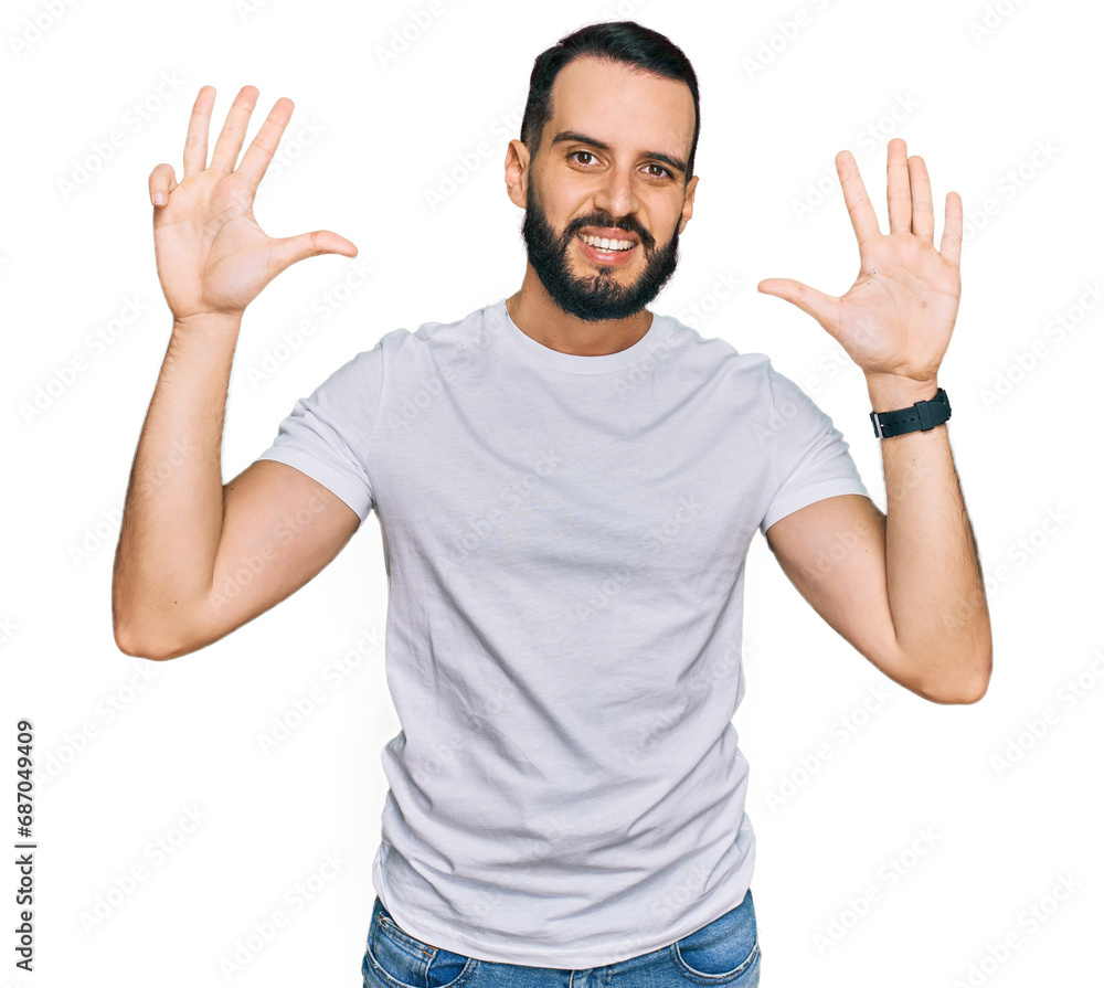 Young man with beard wearing casual white t shirt showing and pointing up with fingers number nine while smiling confident and happy. Young man with beard wearing casual white t shirt showing and pointing up with fingers number nine while smiling confident and happy.