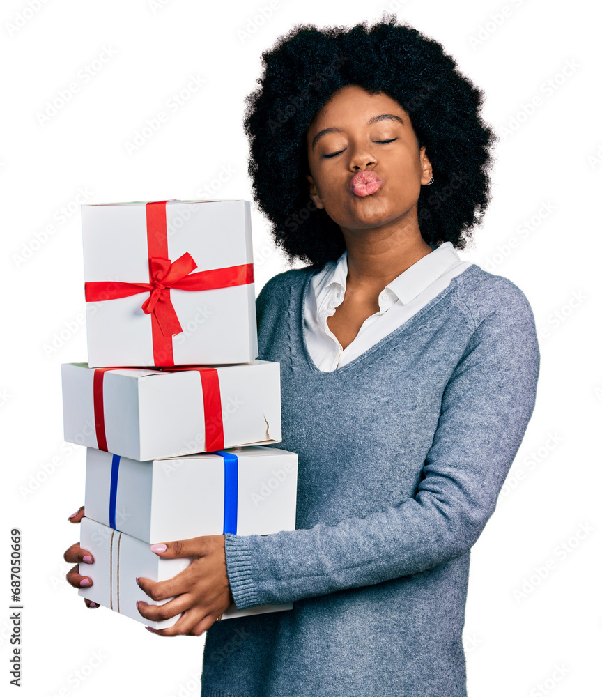 Young african american woman holding gifts looking at the camera blowing a kiss being lovely and sexy. love expression. Young african american woman holding gifts looking at the camera blowing a kiss being lovely and sexy. love expression.