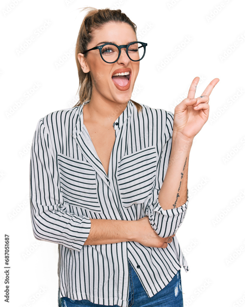 Young caucasian woman wearing business shirt and glasses smiling with happy face winking at the camera doing victory sign. number two.