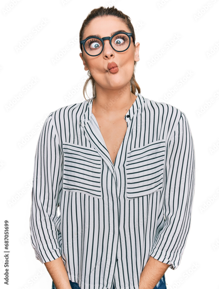 Young caucasian woman wearing business shirt and glasses making fish face with lips, crazy and comical gesture. funny expression.