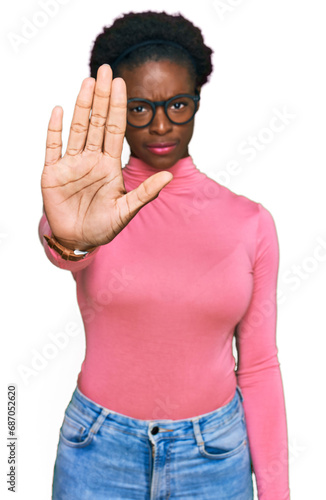 Young african american girl wearing casual clothes and glasses doing stop sing with palm of the hand. warning expression with negative and serious gesture on the face.