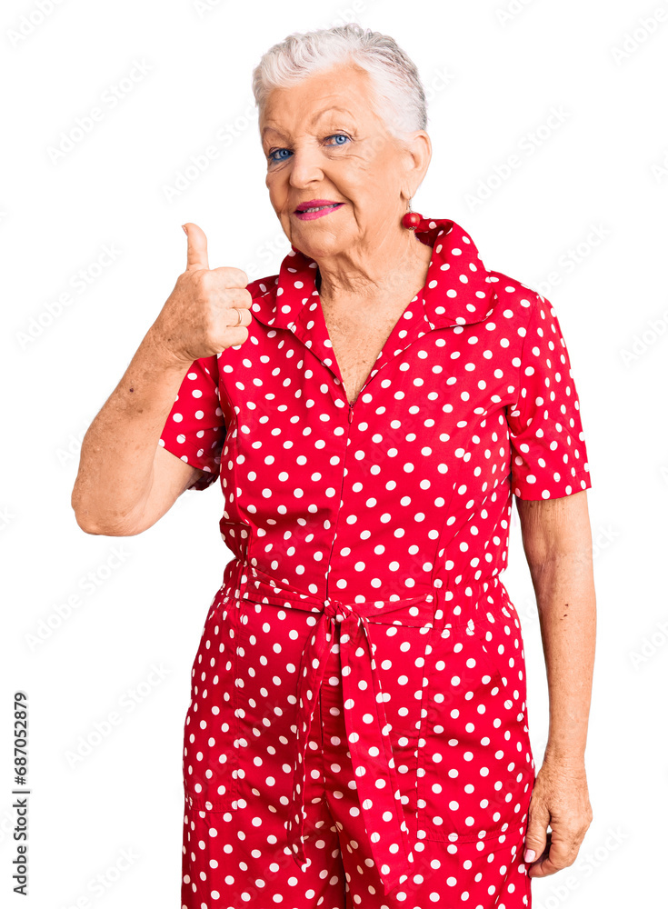 Senior beautiful woman with blue eyes and grey hair wearing a red summer dress doing happy thumbs up gesture with hand. approving expression looking at the camera showing success. Senior beautiful woman with blue eyes and grey hair wearing a red summer dress doing happy thumbs up gesture with hand. approving expression looking at the camera showing success.