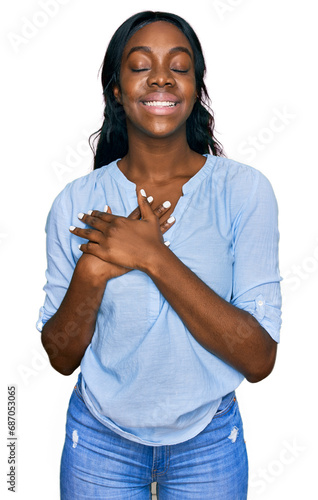 Young african american woman wearing casual clothes smiling with hands on chest with closed eyes and grateful gesture on face. health concept. © Krakenimages.com