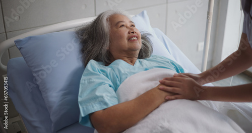 Portrait of Young nurse comforting a senior female patient lying in hospital bed,Caregiver and Lifestyle concept