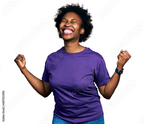 African american woman with afro hair wearing casual purple t shirt very happy and excited doing winner gesture with arms raised, smiling and screaming for success. celebration concept.