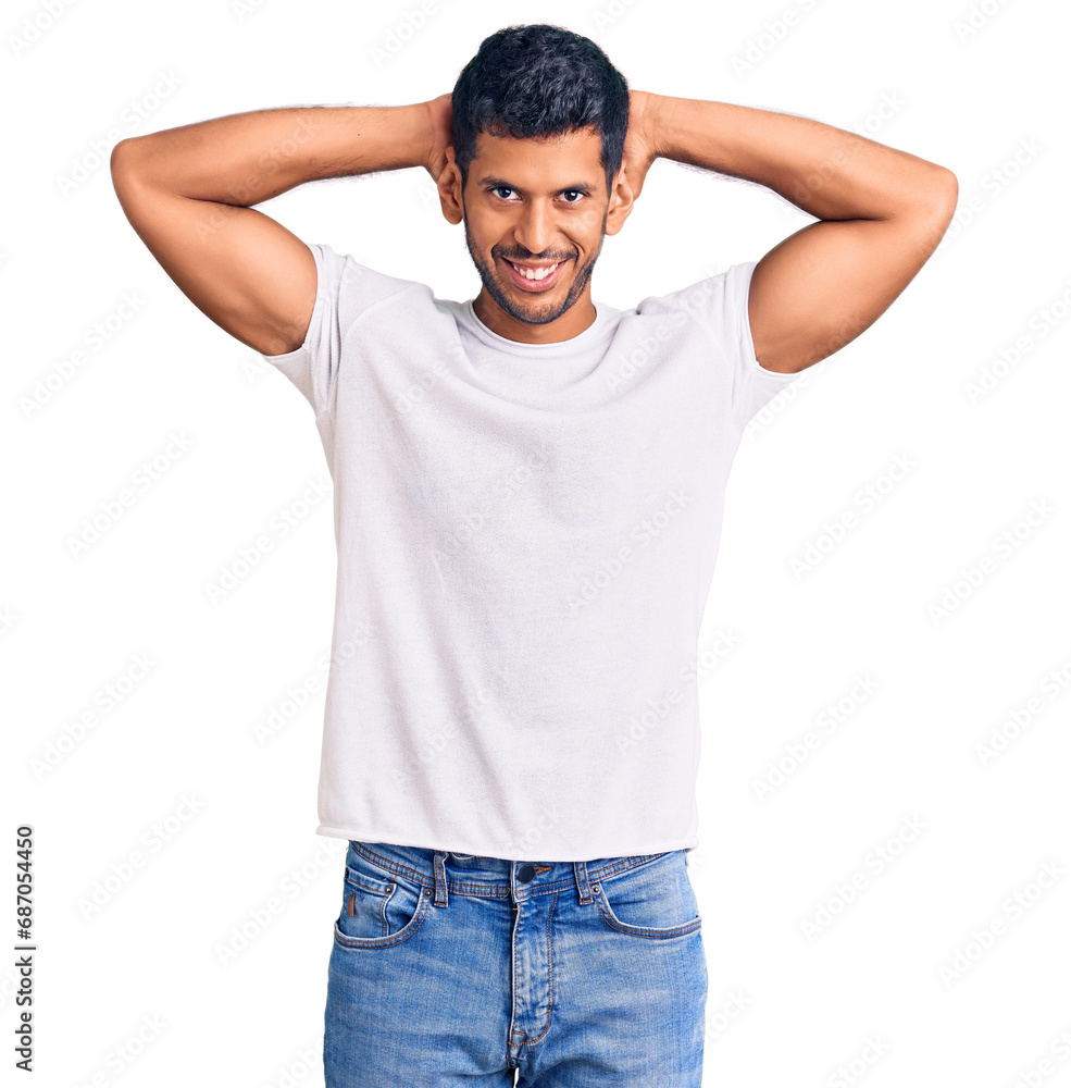 Young latin man wearing casual clothes relaxing and stretching, arms and hands behind head and neck smiling happy Young latin man wearing casual clothes relaxing and stretching, arms and hands behind head and neck smiling happy