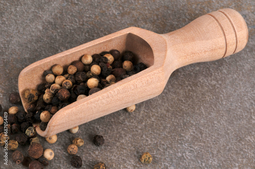 Cuillère en bois de poivre en grains en gros plan sur fond gris