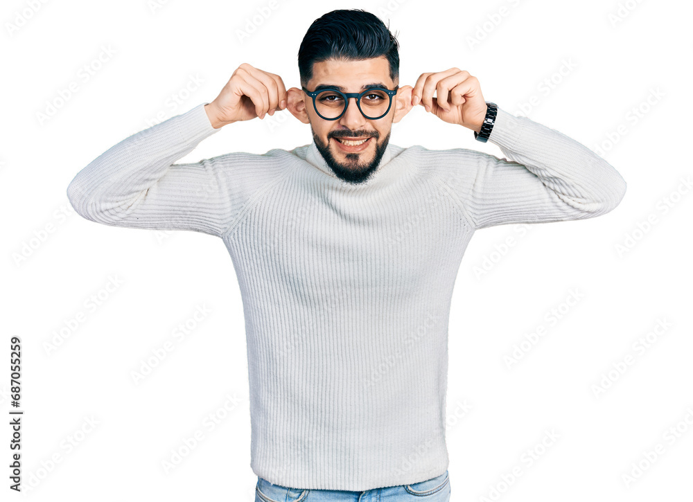 Young arab man with beard wearing elegant turtleneck sweater and glasses smiling pulling ears with fingers, funny gesture. audition problem