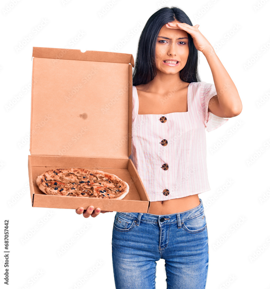 Young beautiful latin girl holding delivery pizza box stressed and frustrated with hand on head, surprised and angry face Young beautiful latin girl holding delivery pizza box stressed and frustrated with hand on head, surprised and angry face