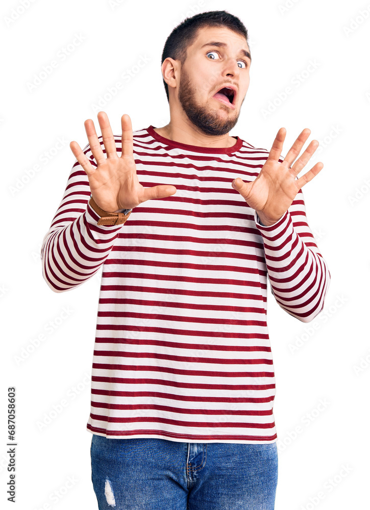 Young handsome man wearing striped sweater afraid and terrified with fear expression stop gesture with hands, shouting in shock. panic concept. Young handsome man wearing striped sweater afraid and terrified with fear expression stop gesture with hands, shouting in shock. panic concept.