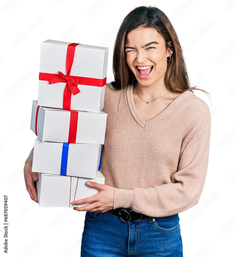Young caucasian girl holding gifts winking looking at the camera with sexy expression, cheerful and happy face. Young caucasian girl holding gifts winking looking at the camera with sexy expression, cheerful and happy face.