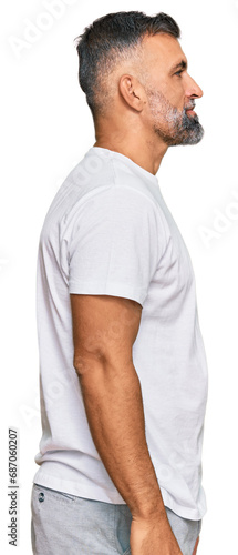 Middle age handsome man wearing casual white tshirt looking to side, relax profile pose with natural face and confident smile.