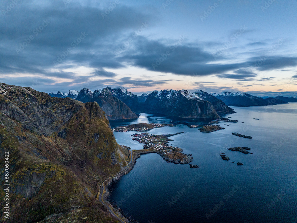 aerial view from the sea over reine fisherman  village on lofoten islands in norway during sunrise with mountains with snow on backgorund