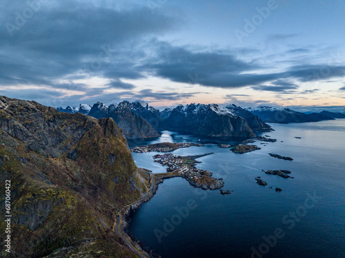 aerial view from the sea over reine fisherman village on lofoten islands in norway during sunrise with mountains with snow on backgorund