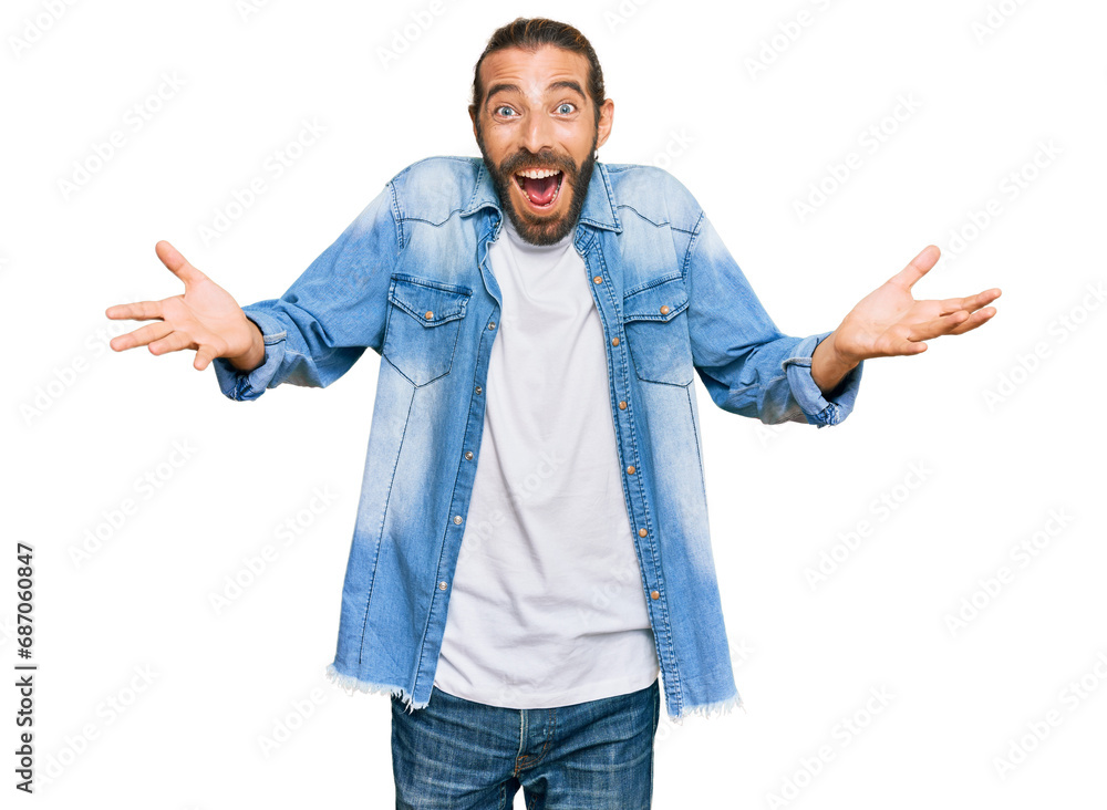 Attractive man with long hair and beard wearing casual denim jacket celebrating crazy and amazed for success with arms raised and open eyes screaming excited. winner concept Attractive man with long hair and beard wearing casual denim jacket celebrating crazy and amazed for success with arms raised and open eyes screaming excited. winner concept