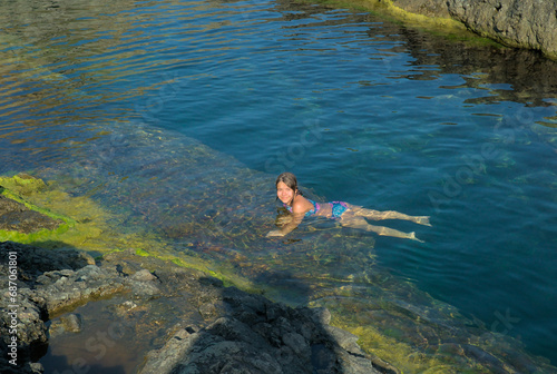 A child swims in the Black Sea among rocks in crystal clear water. Summer holiday at sea, health and entertainment