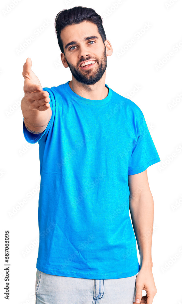 Young handsome man with beard wearing casual t-shirt smiling friendly offering handshake as greeting and welcoming. successful business. Young handsome man with beard wearing casual t-shirt smiling friendly offering handshake as greeting and welcoming. successful business.