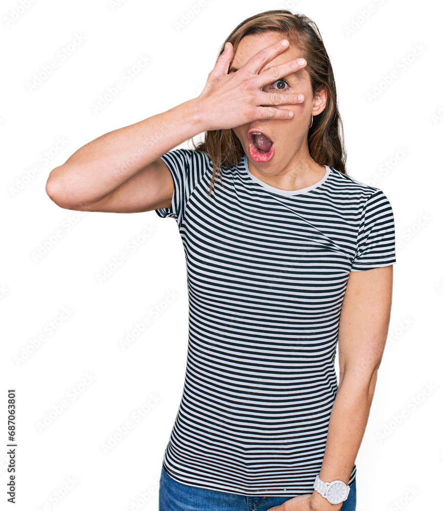Young blonde woman wearing casual clothes peeking in shock covering face and eyes with hand, looking through fingers with embarrassed expression. Young blonde woman wearing casual clothes peeking in shock covering face and eyes with hand, looking through fingers with embarrassed expression.
