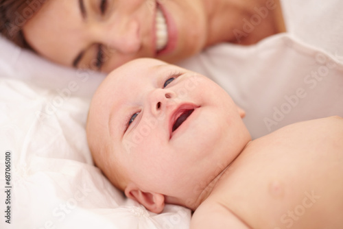 Mother, baby and happiness or love, care and relaxing on bed, bonding and joy in parenthood. Mom, newborn and peace or calm at home, positive and happy for child development, smile and rest together