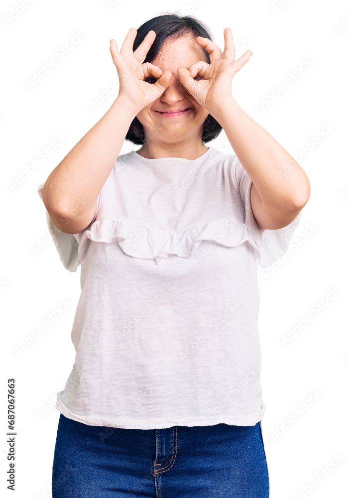 Brunette woman with down syndrome wearing casual white tshirt doing ok gesture like binoculars sticking tongue out, eyes looking through fingers. crazy expression. Brunette woman with down syndrome wearing casual white tshirt doing ok gesture like binoculars sticking tongue out, eyes looking through fingers. crazy expression.