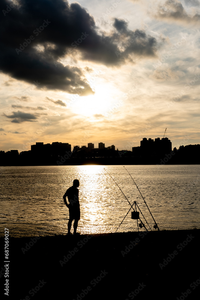 Silhouette of a man, fishing at Han River with the sunsets and view of Seoul city in the background