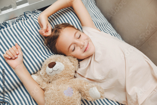 Top view of cute little girl stretching in bed, yawning and rubbing her eyes, waking up early in the morning. Sleep, awakening and relaxation concept