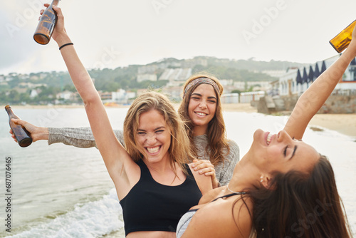 Happy girlfriends with beer on beach photo
