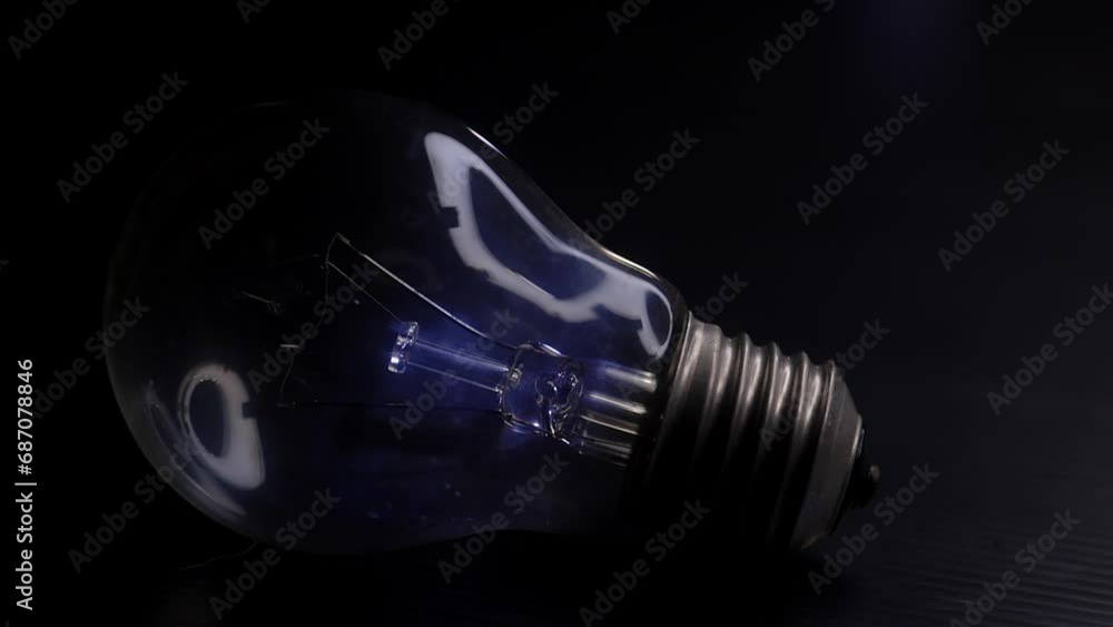 Classic electric ligth bulb lying on a black surface and shifting light reflection in the bulb- macro shot Classic electric ligth bulb lying on a black surface and shifting light reflection in the bulb- macro shot