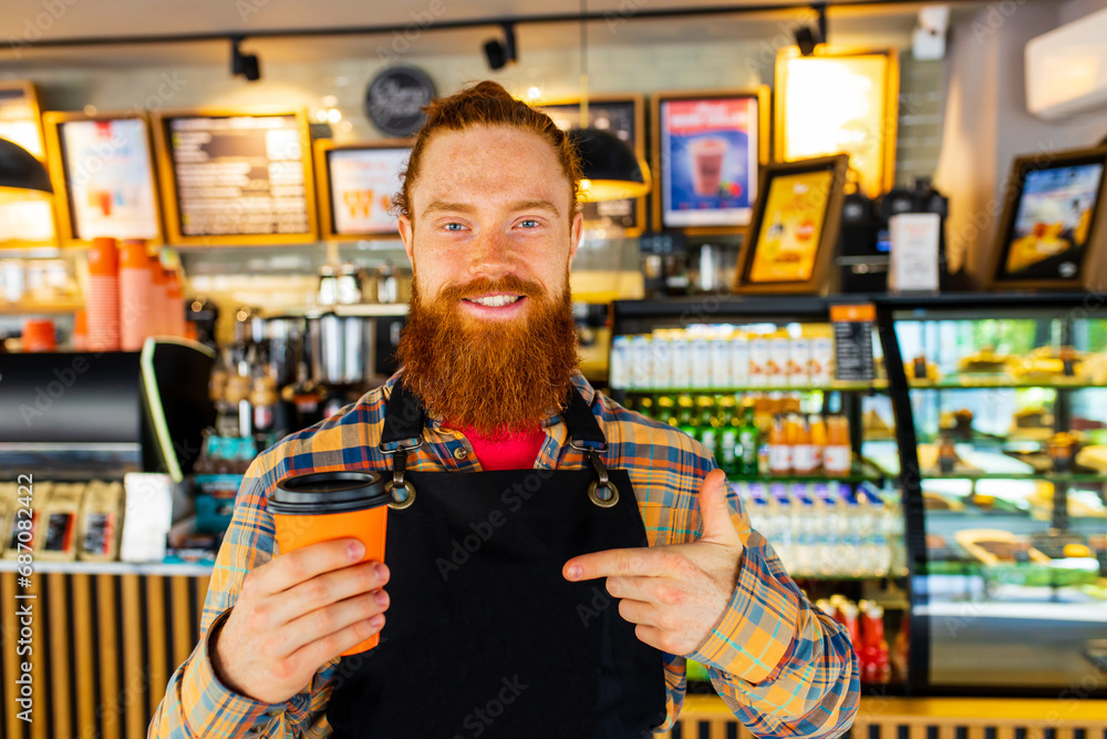 Professional barista young redhaired ginger bearded man in black apron working in coffee shop Professional barista young redhaired ginger bearded man in black apron working in coffee shop