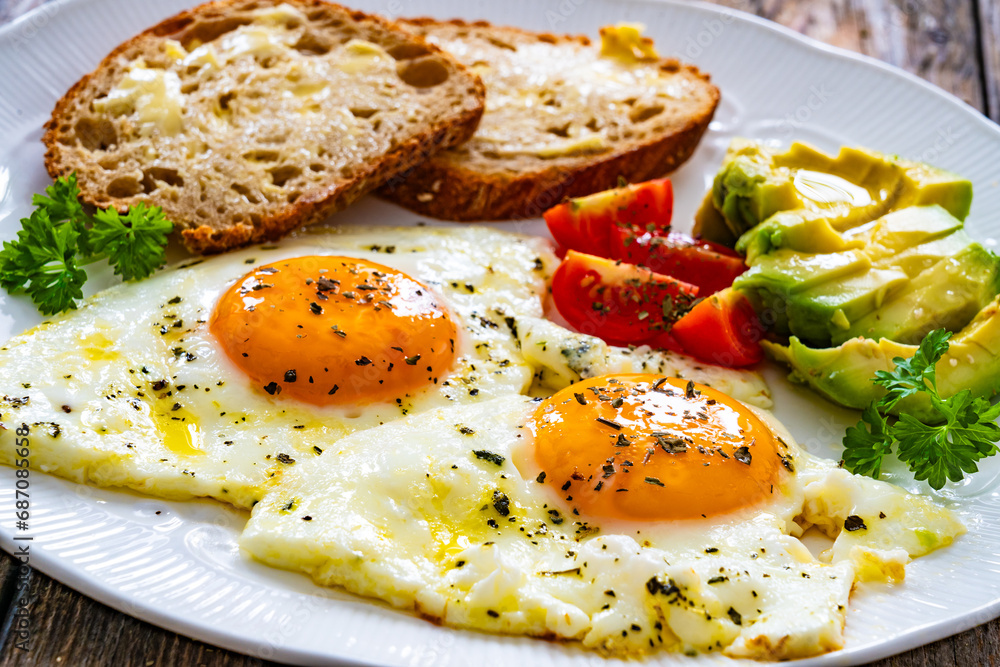 Breakfast - sunny side up egg, toasted bread and avocado served on wooden table
Breakfast - sunny side up egg, toasted bread and avocado served on wooden table