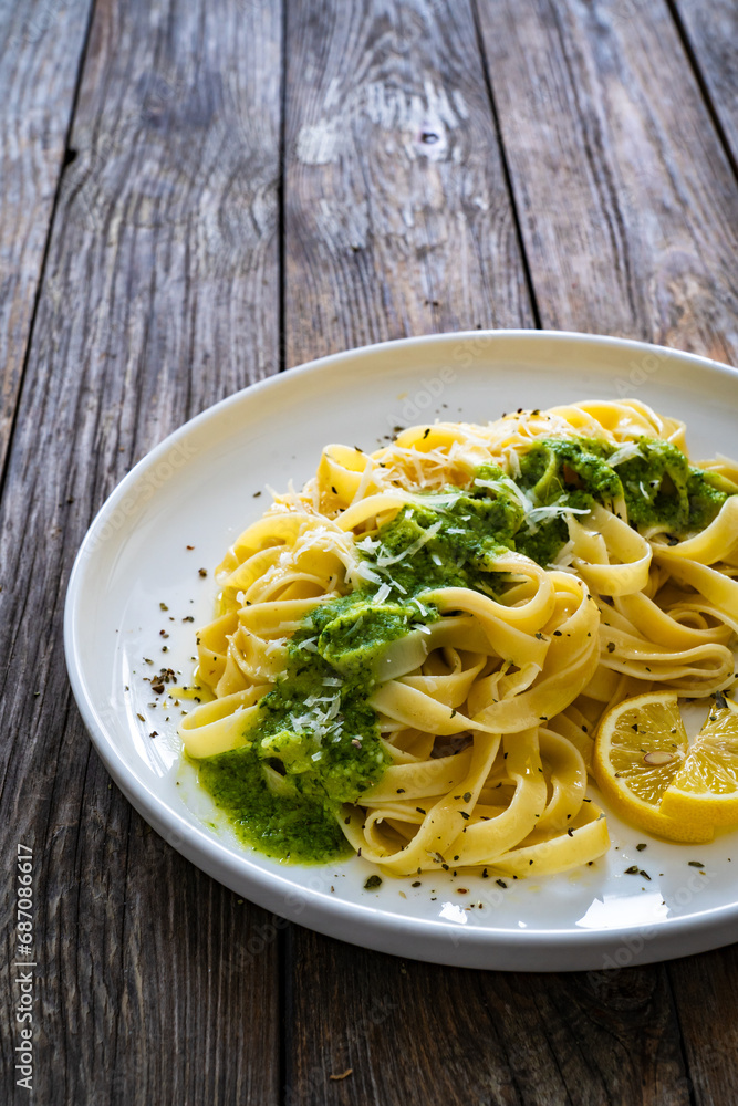 Tagliatelle with basil pesto sauce on wooden table