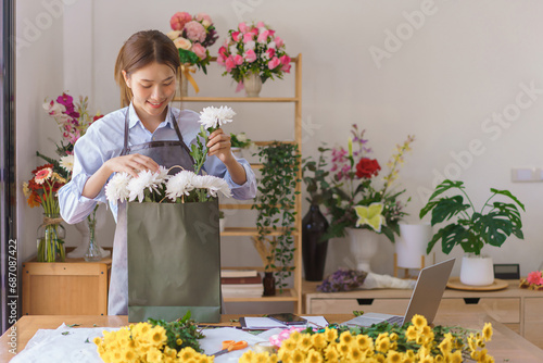 Florist concept, Woman florist arranged bouquet white chrysanthemum in paper bag at flower shop