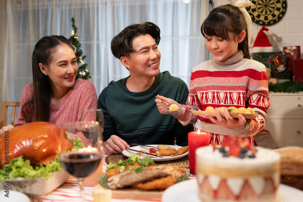 Happy Asian family mother, father and daughter having dinner celebrating Christmas at home