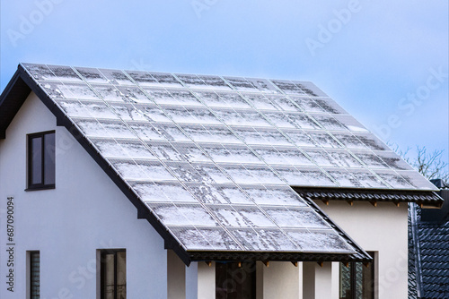 Solar Panels Roof House under Snow Cover in Winter. Snow Covered Solar Batteries on Rooftop of Residential House.
