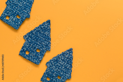 Blue mini crochet houses on a yellow background. Top view. Copy space.