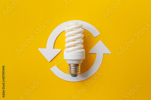Energy saving light bulb and recycle arrows. Economical consumption of electricity. Orange background . The concept of nature conservation and renewable energy sources