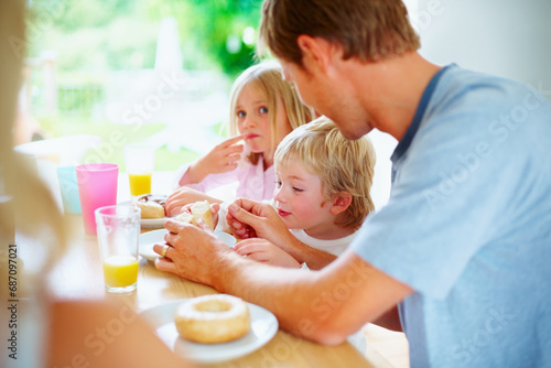 Breakfast, kids and father eating donut at table together, love and bonding in home in the morning. Family, young children and dad with pastry, dessert or junk food sweets for sugar meal in house