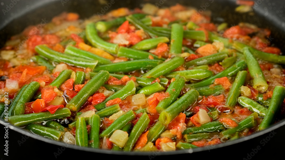 Frying in pan vegetables green beans, tomatoes, bell peppers