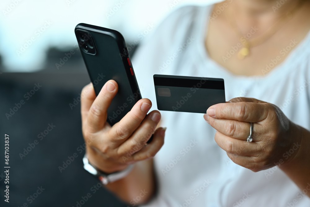 Close-up old woman's hands customer enters credit card code to pay online shopping, internet purchases, or payments via smartphone, Online banking concept