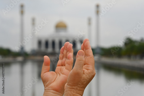 Close-up Muslim woman hands praying with Central Mosque of Songkhla Province, Thailand at the background photo