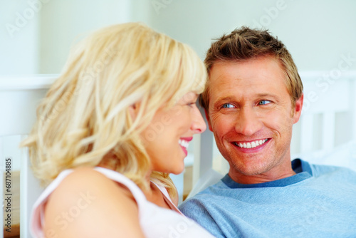 Couple, face and smile in bed of home for love, care and relax for holiday, break and wake up together. Man, woman and bedroom in morning for happy relationship, freedom and bonding with partner
