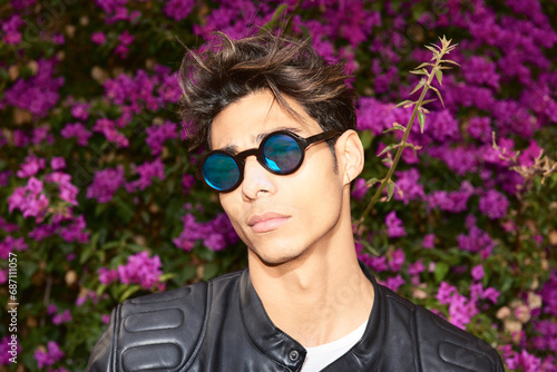 Portrait of a handsome serious latin man wearing sunglasses and leather jacket looking at camera photo