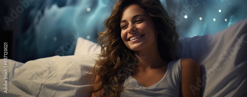 A beautiful girl with wavy hair lies in bed on a pillow and smiles. Theme of healthy sleep and rest. © Boomanoid