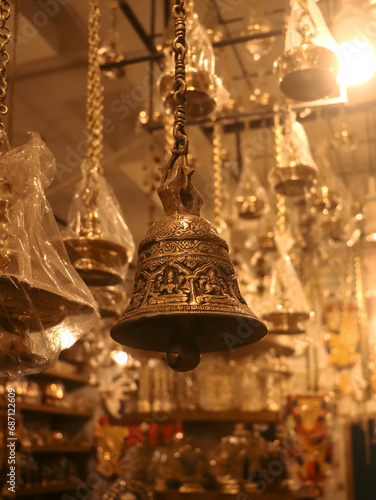 decorative brass bell hanging on a chain inside a antique shop selling handcrafted objects in the market near the temple