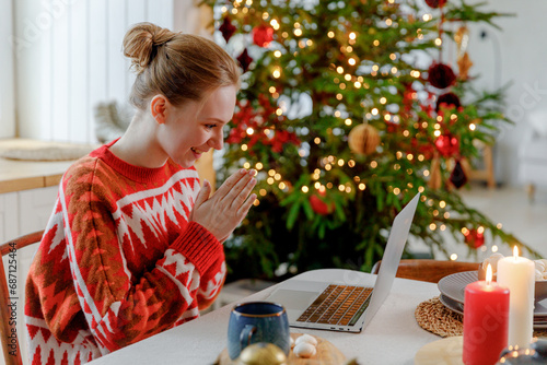 Фотография young blonde woman sits at table in kitchen with Christmas tree, gets unexpected great news, feels elation and thrilled
