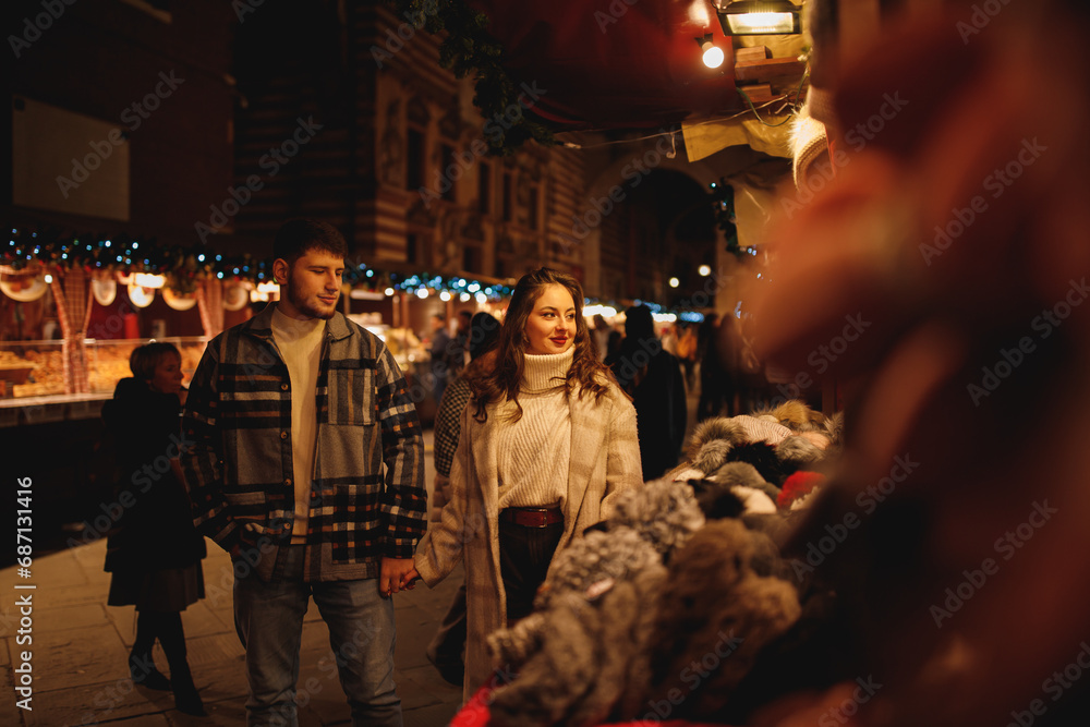 Young stylish couple in love in checkered coats at Christmas market in Verona 