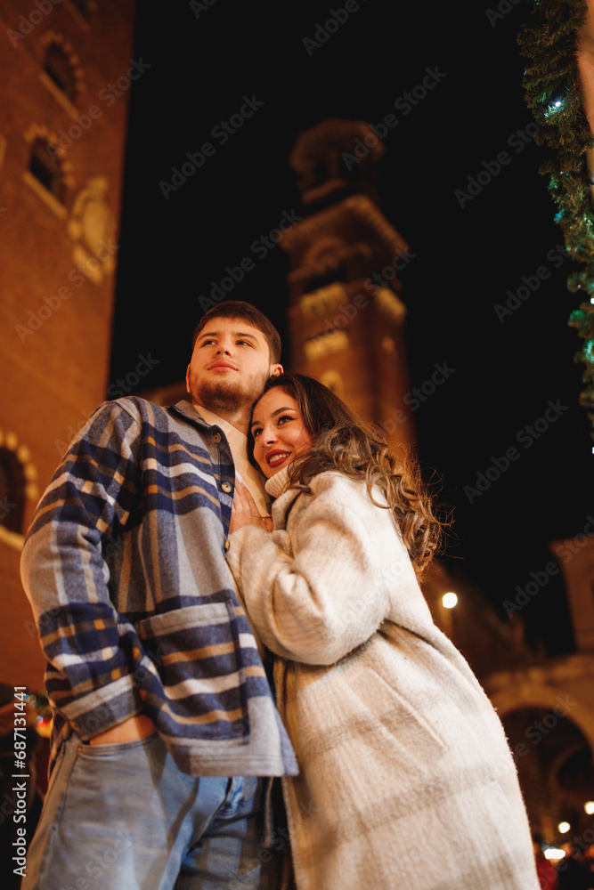 Young stylish couple in love in checkered coats in Verona at Piazza dei Signori